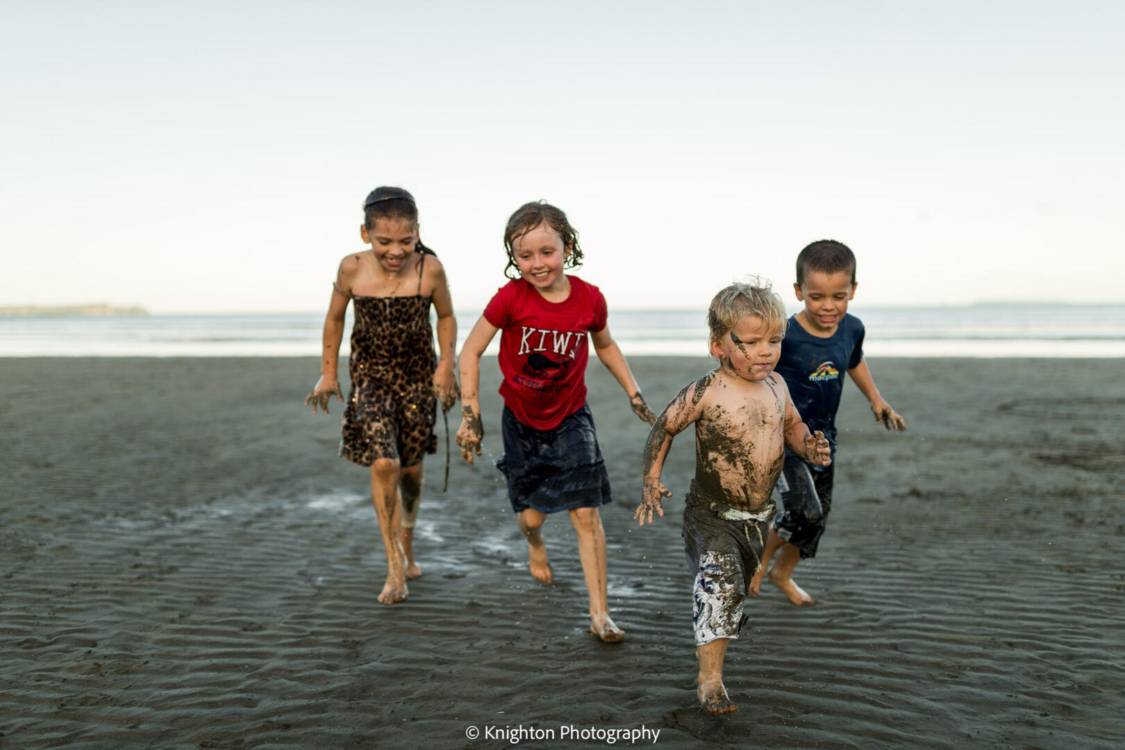 Friends playing at the beach at sunset